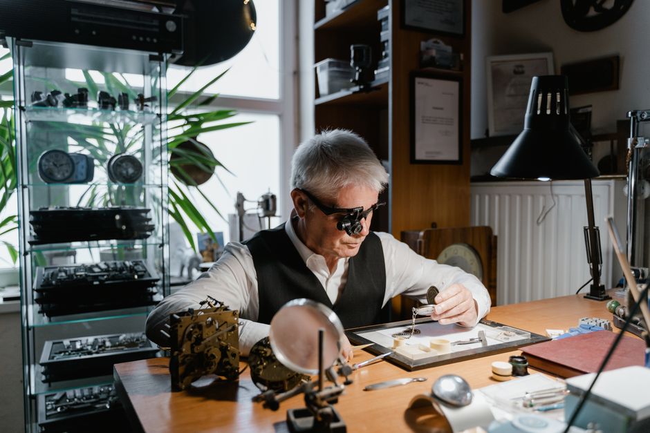 Watchmaker focused on repairing a timepiece in his workshop, showcasing precision and expertise.